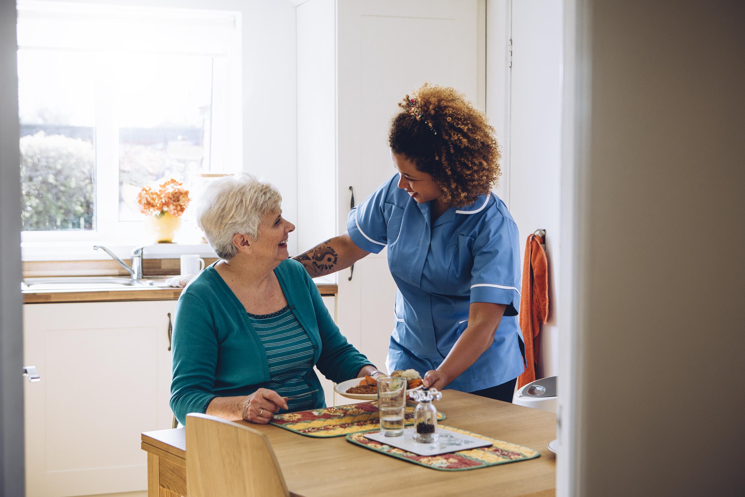 Care worker assisting participant with meal preparation at home